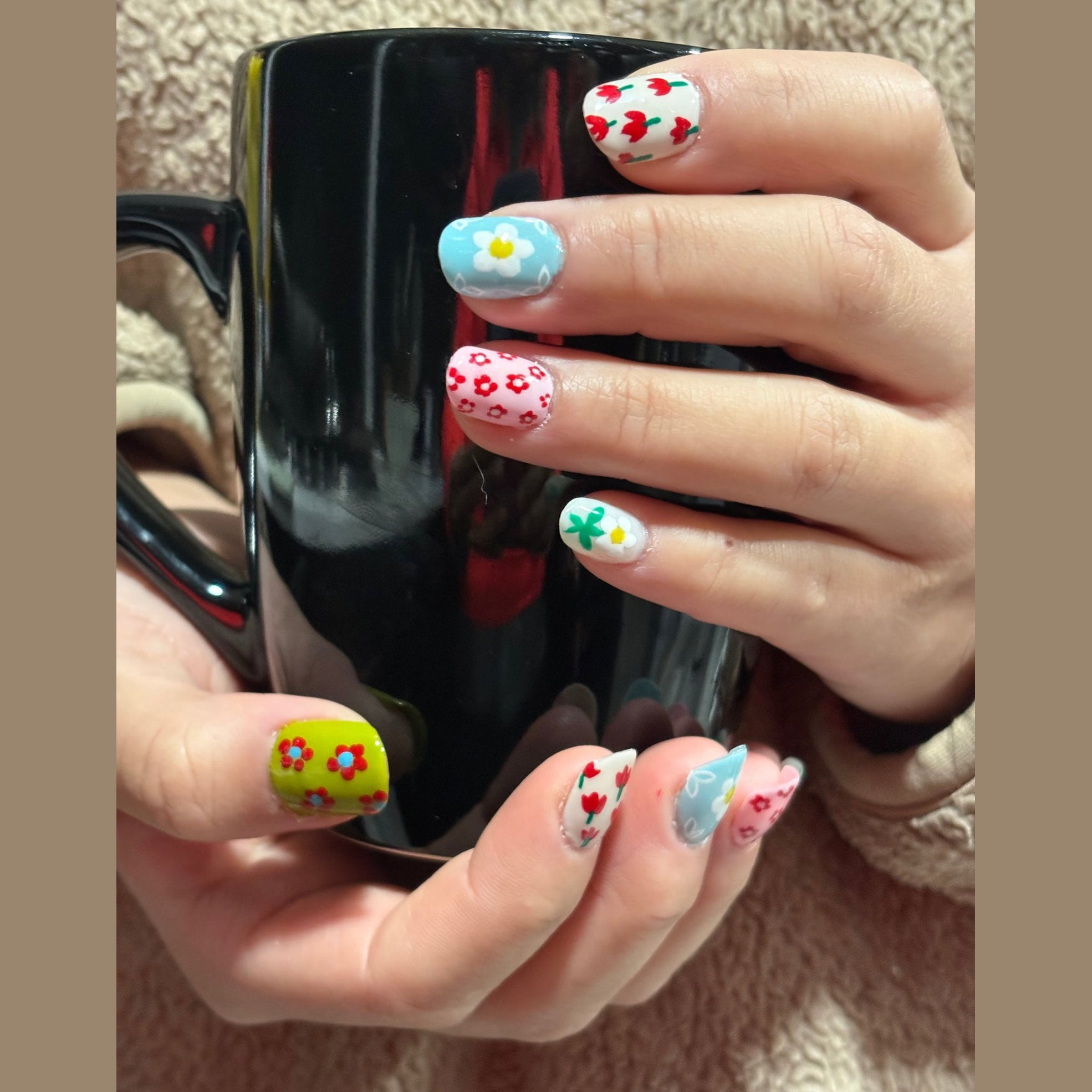 A cheerful, hand-painted mix of tiny flowers, hearts, and clovers in red, blue, white, and lime green, inspired by sketchbook studies of a spring garden. Each nail is slightly different, like pages from an artist’s notebook, so the set feels playful rather than perfectly matching. The base tones are light and bright, flattering especially on light to medium skin tones; on deeper skin, the colors will read bolder and more graphic rather than soft.